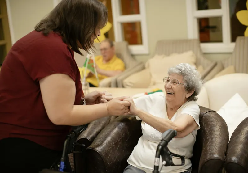 A caregiver helping an elderly woman with a walker